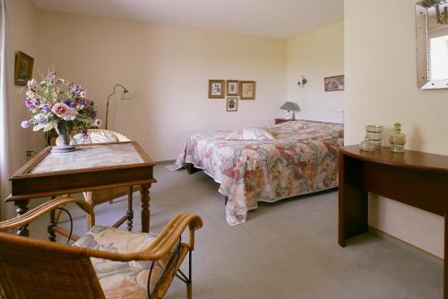 een hotelkamer met 2 bedden en een tafel en een bureau met bloemen erop bij De Traverse in Bemelen