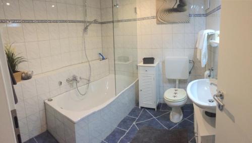 ein Badezimmer mit einer Badewanne, einem WC und einem Waschbecken in der Unterkunft Ferienwohnung Kramergasse in Garmisch-Partenkirchen
