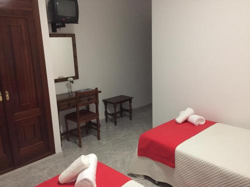 a room with two beds and a desk and a television at Hotel Florida in A Lanzada