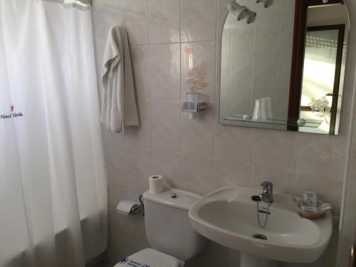 a bathroom with a toilet and a sink and a mirror at Hotel Florida in A Lanzada