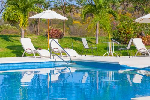 a pool with chairs and umbrellas next to the water at Mansiones Cruz del Mar Huatulco in Santa Cruz Huatulco
