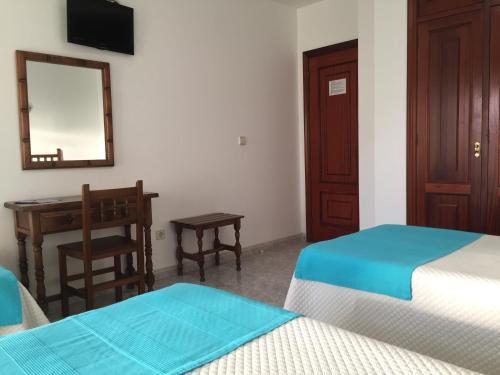 a room with two beds and a desk and a mirror at Hotel Florida in A Lanzada