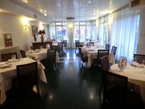 une salle à manger avec des tables blanches, des chaises et des fenêtres dans l'établissement Valentino b&b, à Portogruaro