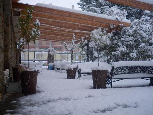 two benches covered in snow in a yard at Hostal Vall D'Aneu by Arcas & Sambola in Esterri d'Àneu
