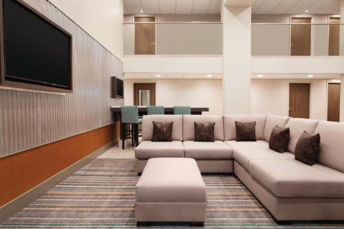 a waiting room with a couch and a flat screen tv at Radisson Hotel Charlotte Airport in Charlotte