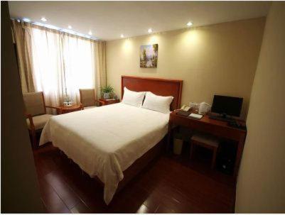 a bedroom with a bed and a desk with a computer at GreenTree Inn Rizhao West Station Suning Plaza in Rizhao