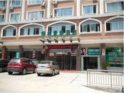 two cars parked in front of a large building at GreenTree Inn Rizhao West Station Suning Plaza in Rizhao