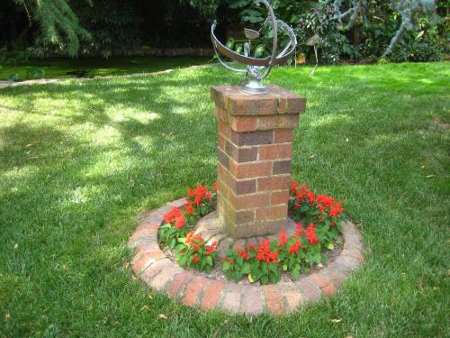 a statue in a brick pillar with red flowers at Bungunyah Apartments in Croydon