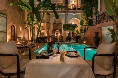 una mesa y sillas frente a una piscina en Indian Palace, en Marrakech