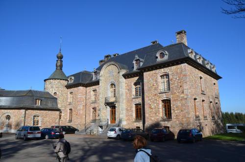 a large brick building with cars parked in a parking lot at B&B Nord Sud in Salmchâteau