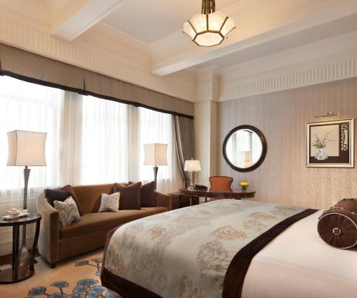 a bedroom with a large bed and a couch at Fairmont Peace Hotel on the Bund in Shanghai