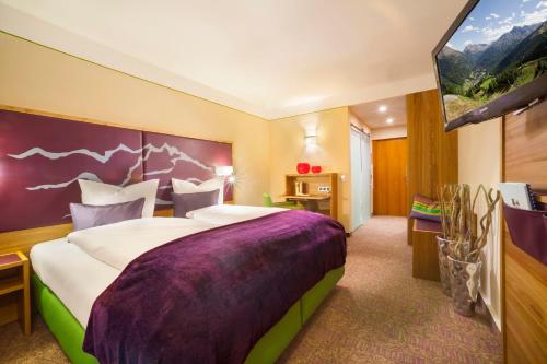 a hotel room with a large bed and a flat screen tv at Hotel Raphael im Allgäu in Kempten