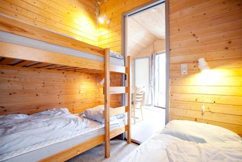 a bedroom with two bunk beds in a wooden cabin at Svalereden Strand Camping Cottages in Frederikshavn