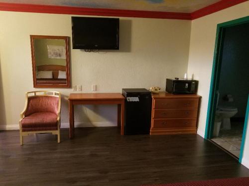 a room with a desk and a tv and a chair at Super 7 Motel in Anaheim