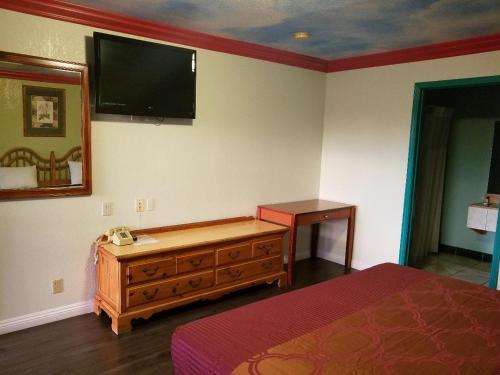 a bedroom with a bed and a television on the wall at Super 7 Motel in Anaheim