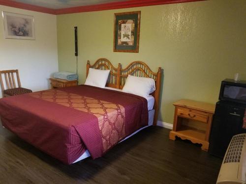 a bedroom with a bed and a table and a television at Super 7 Motel in Anaheim