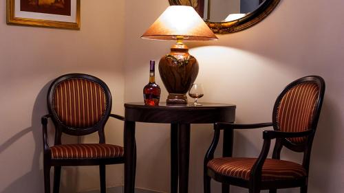 a table with two chairs and a lamp and a bottle of wine at Hotel Maroon in Zagreb