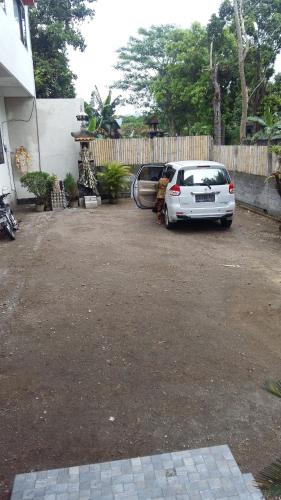 a white car parked in a driveway next to a fence at Anyar in Mataram