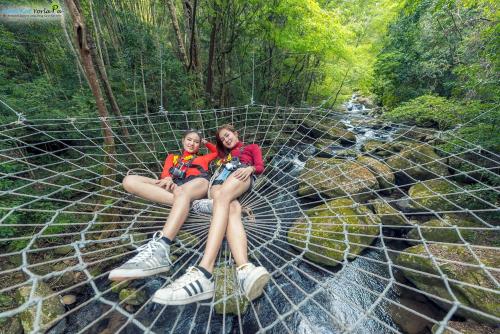 two women sitting on a net in a forest at Namkat Yorla Pa Resort in Ban Kat