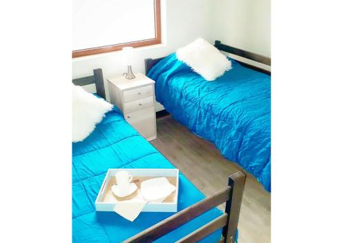 a bedroom with two beds with blue sheets and a table at Edificio Reñaka Beach 248 in Viña del Mar