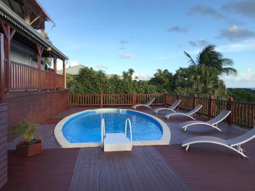 a swimming pool with chairs around it on a deck at La Colombine in Sainte-Anne