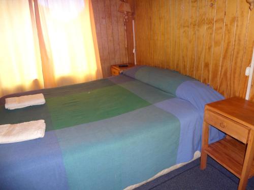 a bedroom with a bed with a blue and green blanket at Cabañas Don Hugo in Ancud