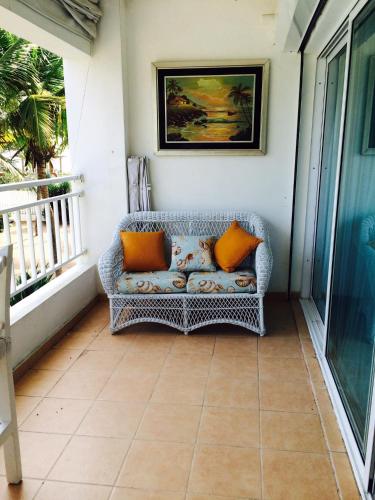 a wicker couch sitting on a porch with orange pillows at Apartamento Juan Dolio in Juan Dolio