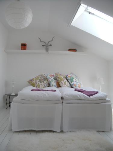 a white bed with pillows on it in a room at Casa Kruttornet & Villa Fiskarporten in Visby