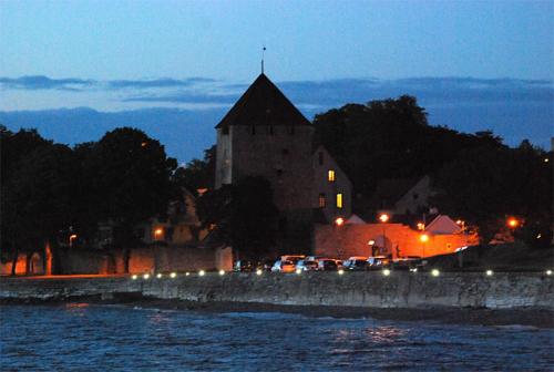 a large building with cars parked near the water at night at Casa Kruttornet & Villa Fiskarporten in Visby