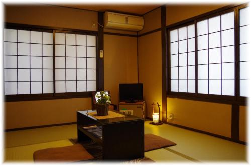 a room with large windows and a table and a tv at Ryoso Chatani in Kyoto