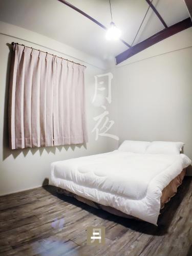 a bedroom with a white bed and a window at Feb hostel in Tainan