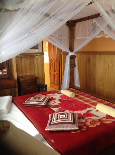 a bedroom with a bed with a red and white comforter at Highcliffe Guest House in Haputale