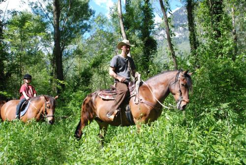 Due persone cavalcano cavalli in un campo di Agriturismo La Finca a Cresciano