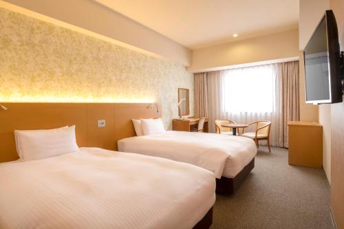 a hotel room with two beds and a television at Chisun Grand Nagano in Nagano