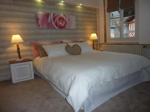 a large white bed with a teddy bear on it at Hotel le P'tit Beaumont in Beaumont-en-Auge