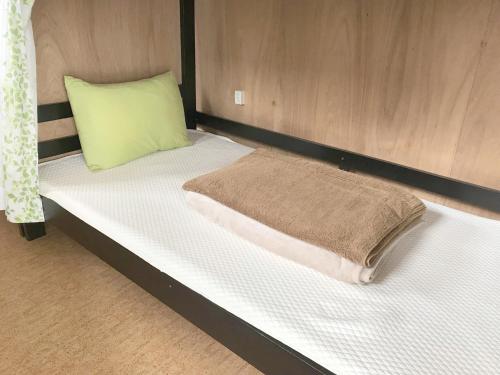 - un lit avec un oreiller vert dans l'établissement Matsukaze The Guest House Ishigaki, à Ishigaki