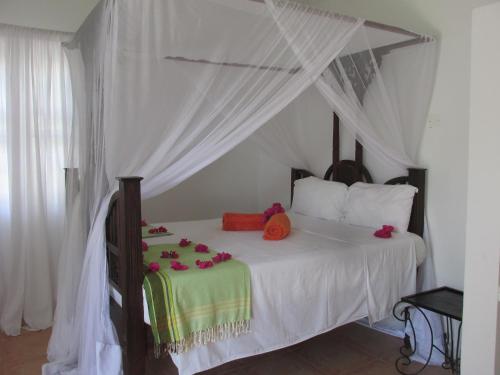 a bedroom with a canopy bed with flowers on it at Driftwood Beach Lodge in Jambiani