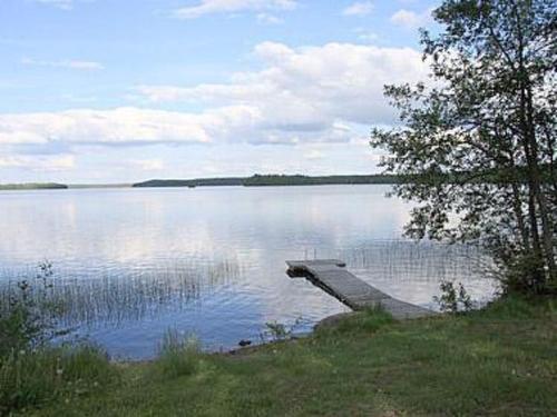 a bench sitting on the shore of a lake at Holiday Home Pihlajatupa by Interhome in Kittilä