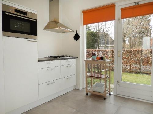 een keuken met witte kasten en een raam bij Holiday Home de Witte Raaf-2 by Interhome in Noordwijk