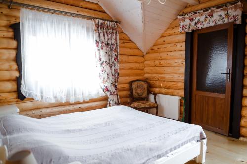 Dormitorio con cama y ventana en una cabaña de madera en Provintsia, en Migovo
