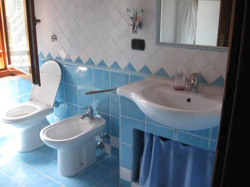 un bagno blu e bianco con lavandino e servizi igienici di Villetta fronte mare ad Arbus