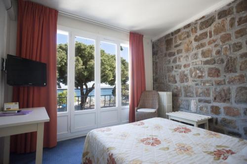 Habitación de hotel con cama y ventana en Hôtel Le Richiardi, en Carqueiranne