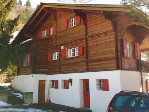ein großes Holzhaus mit roten Fensterläden in der Unterkunft Apartment Bärnermutz # 2 by Interhome in Lenk im Simmental
