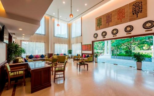 a large lobby with chairs and tables and windows at Regenta Central Herald Mysore in Mysore