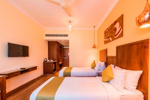 a hotel room with two beds and a television at Regenta Central Herald Mysore in Mysore