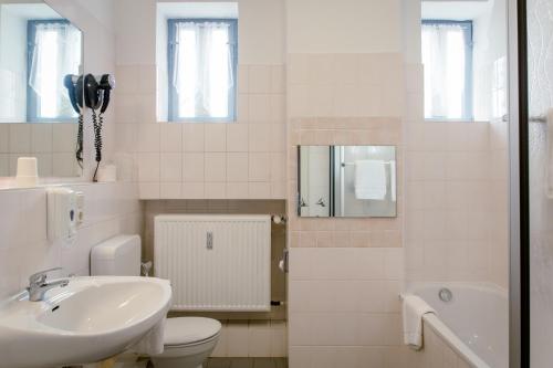 a white bathroom with a sink and a toilet at Hotel Handelshof in Bünde