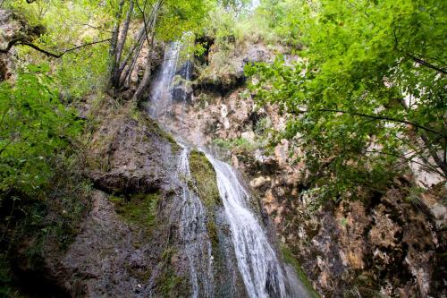 einen Wasserfall an der Seite eines Berges mit Bäumen in der Unterkunft Mobile home Camp vikendica Slapnica u Parku prirode Žumberak i Samoborsko gorje in Krašić