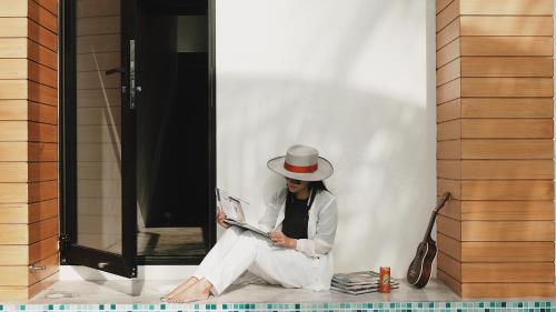 a woman sitting on the floor reading a magazine at Book a Bed Poshtel - SHA Plus in Phuket Town