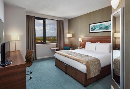 ミルトン・キーンズにあるLeonardo Hotel Milton Keynesのベッド、デスク、テレビが備わるホテルルームです。