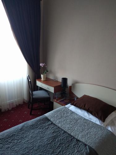 a hotel room with a bed and a desk and a chair at Kaiser Hotel in Chernivtsi